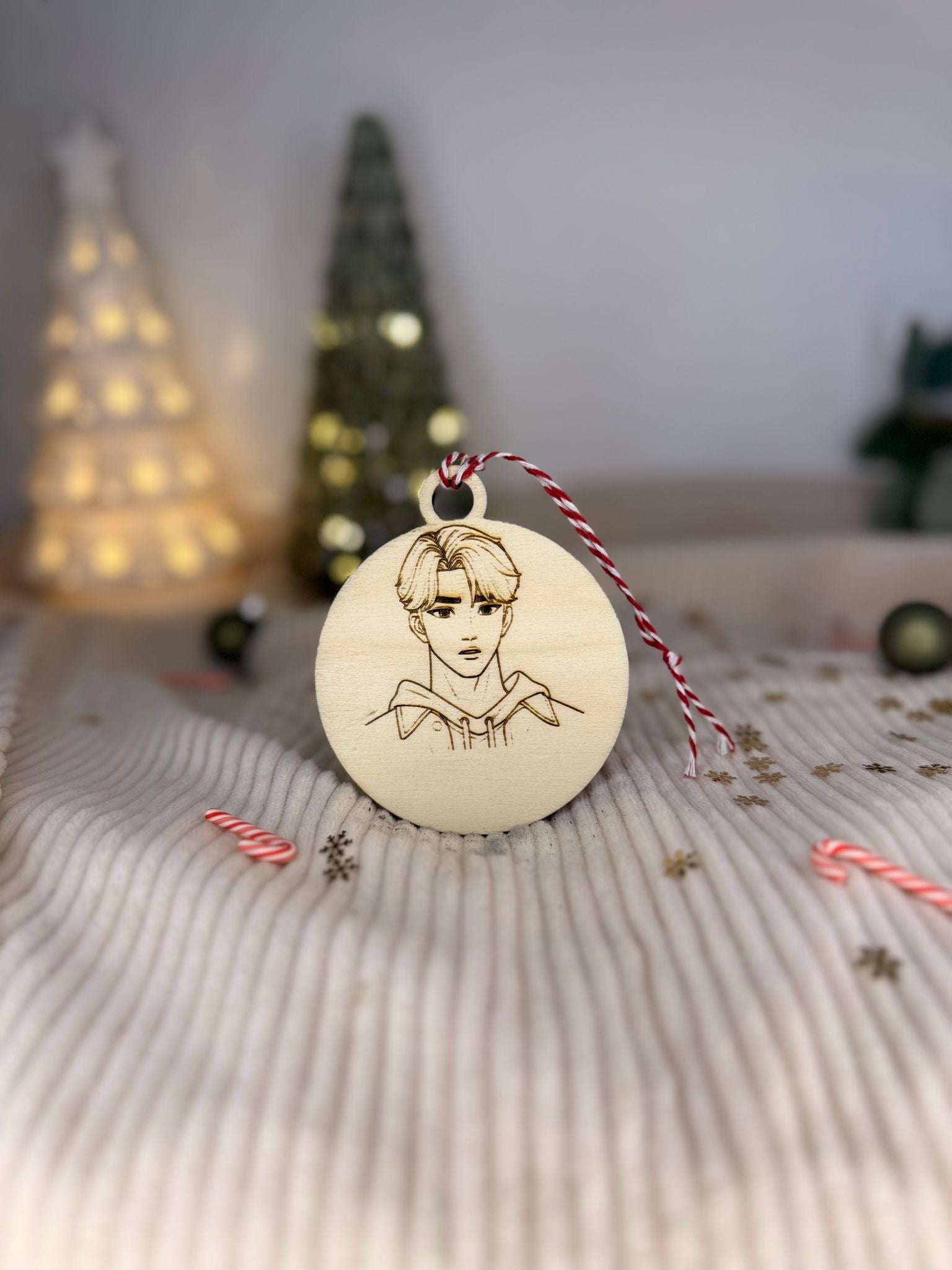 Boule de Noël en bois personnalisée au nom d’un fan de K-pop, suspendue dans un sapin illuminé pour une touche unique et moderne.