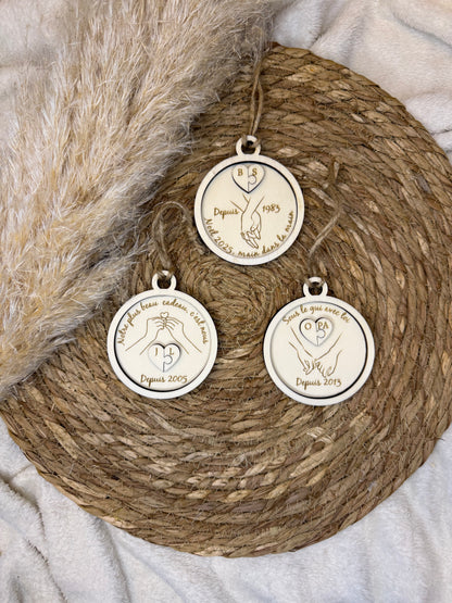 Boule de Noël artisanale en bois présentant deux pièces de puzzle gravées avec les initiales des amoureux, idéale pour un cadeau unique.