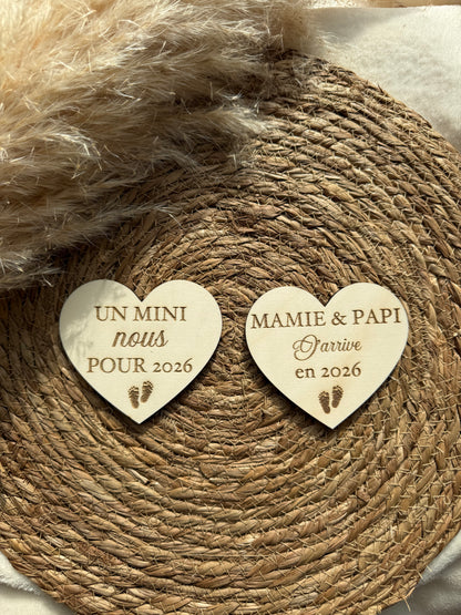 Gros plan sur une carte en bois en forme de cœur gravée avec un prénom et un message de bienvenue, fabrication artisanale.