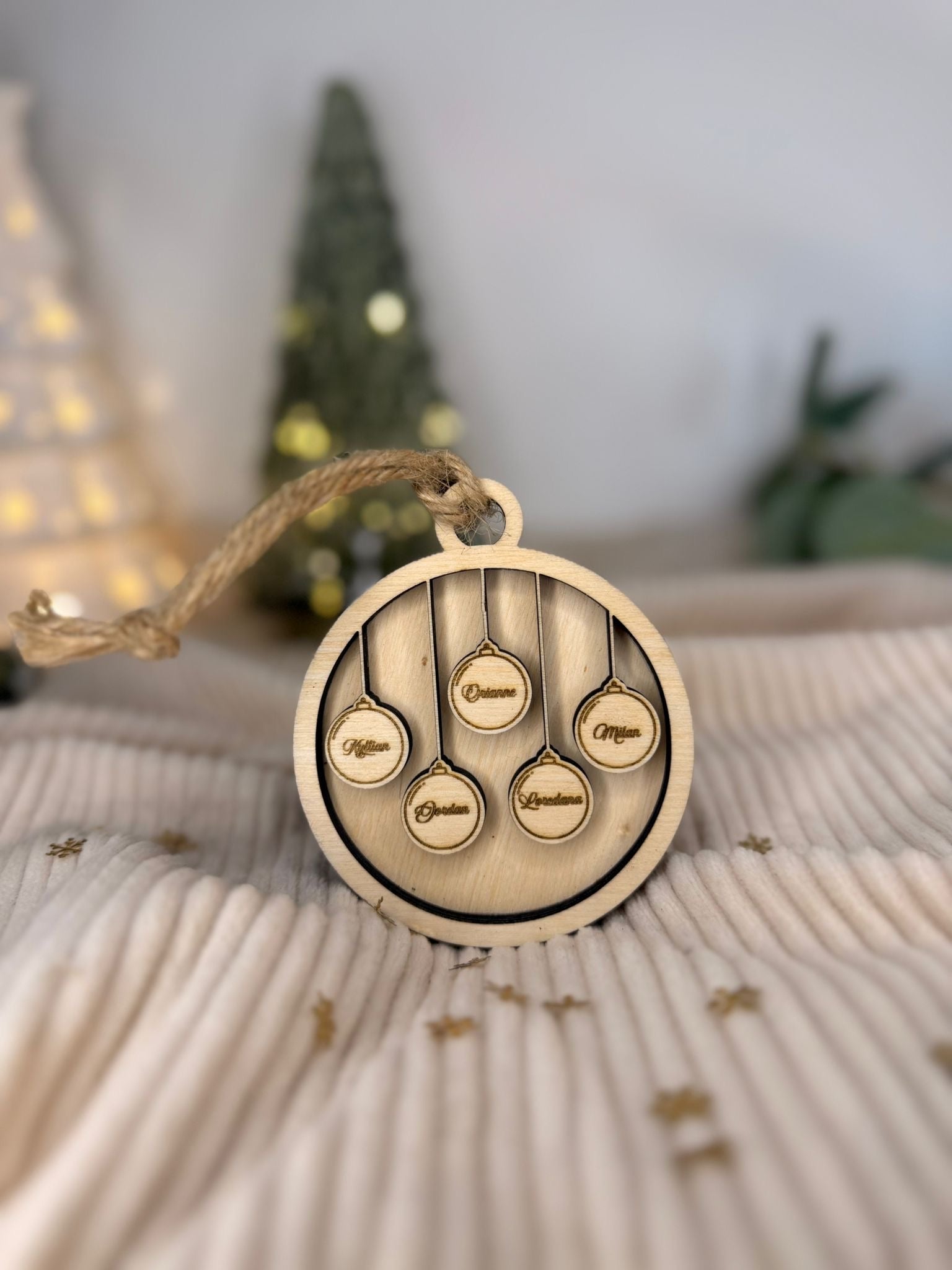 Détail de la gravure laser sur une boule de Noël familiale, montrant la précision et la beauté du travail artisanal.